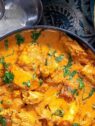 Butter Chicken served in a navy bowl with a side of naan